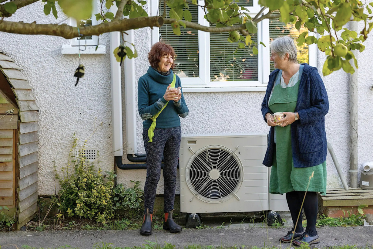 Two people chatting next to a heat pump