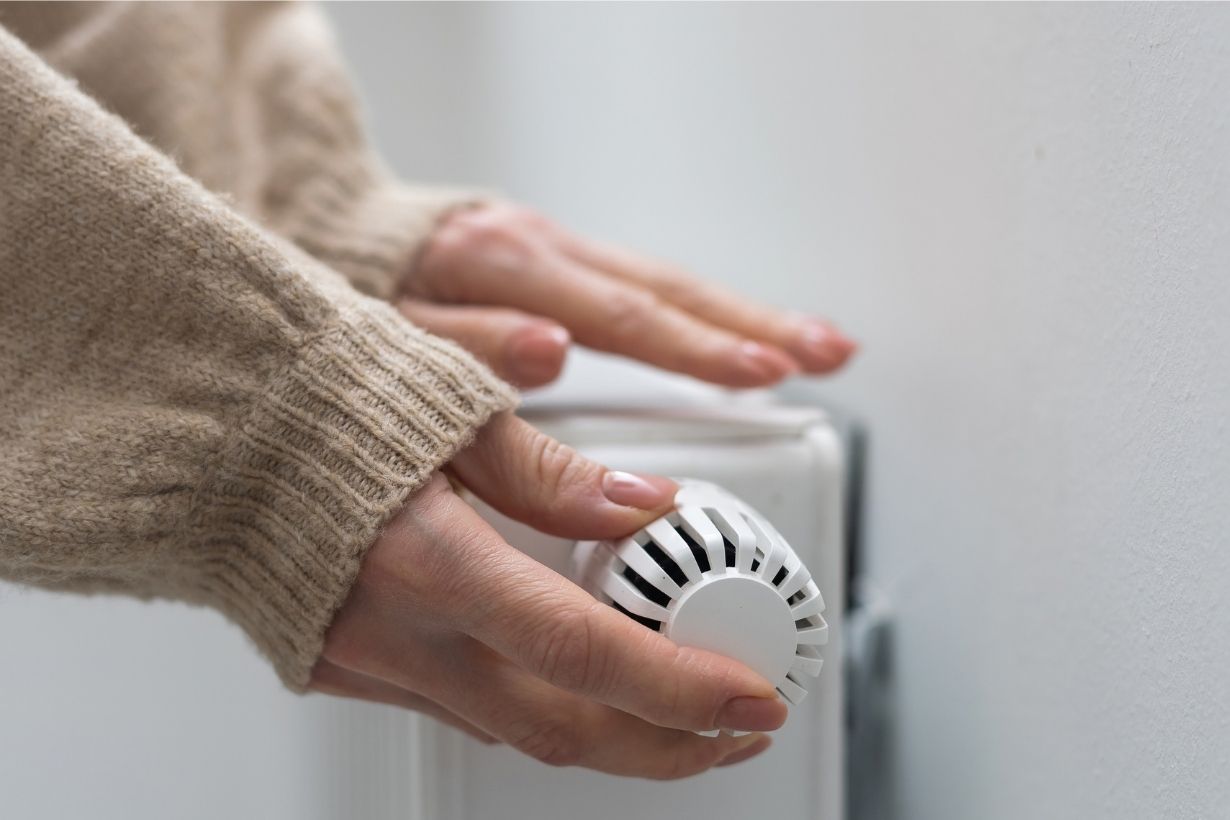 Person adjusting a radiator thermostat.
