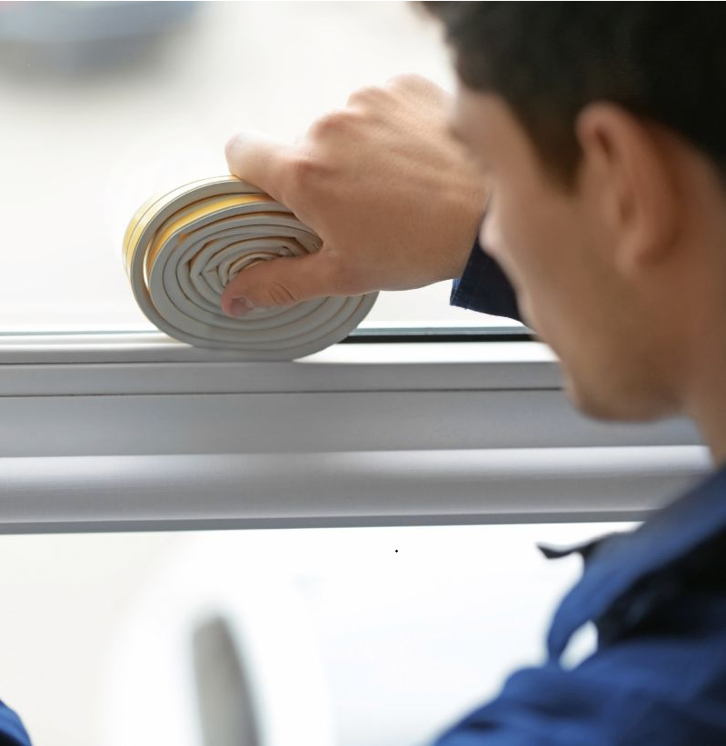 Man adding insulation tape to a window frame