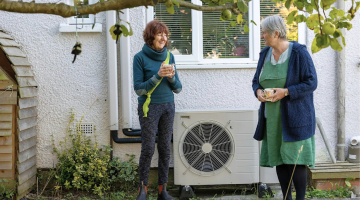 Two people chatting next to a heat pump